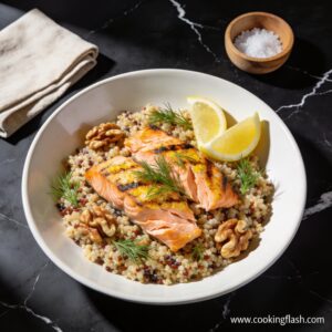 Beautifully plated high protein grilled salmon and quinoa salad with walnuts featuring charred salmon flakes and toasted walnuts on black marble countertop