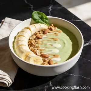 Beautifully styled high protein smoothie bowl with almond milk and vanilla topped with banana and granola on black marble countertop